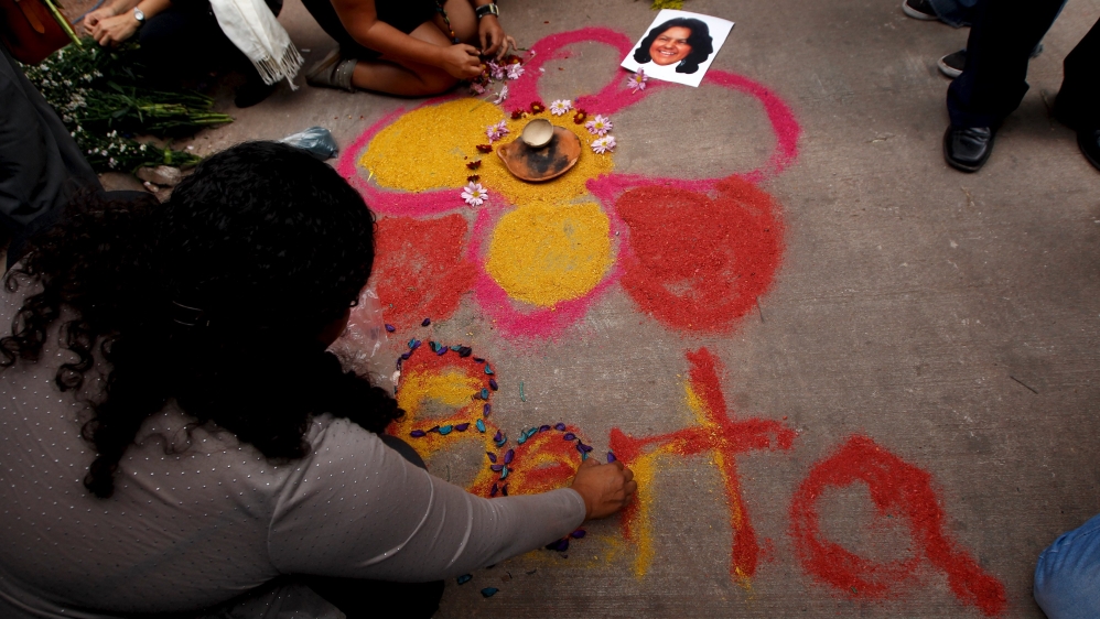 Activists draw a flower on the floor with chalk as part of a makeshift altar for slain environmental rights activist Berta Caceres during a protest outside the morgue in Tegucigalpa