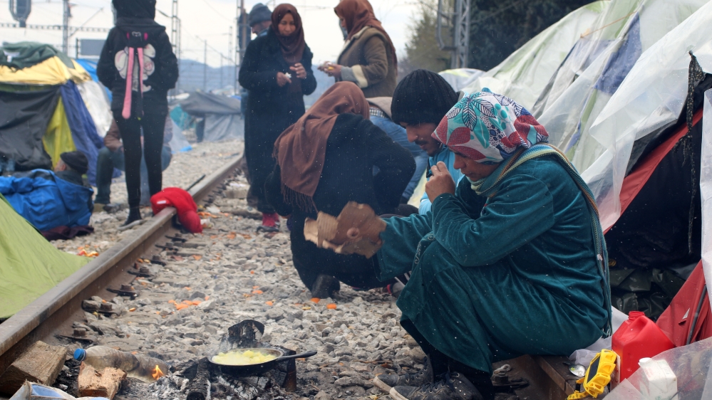 A woman cooks potatoes on a fire [John Psaropoulos/Al Jazeera]