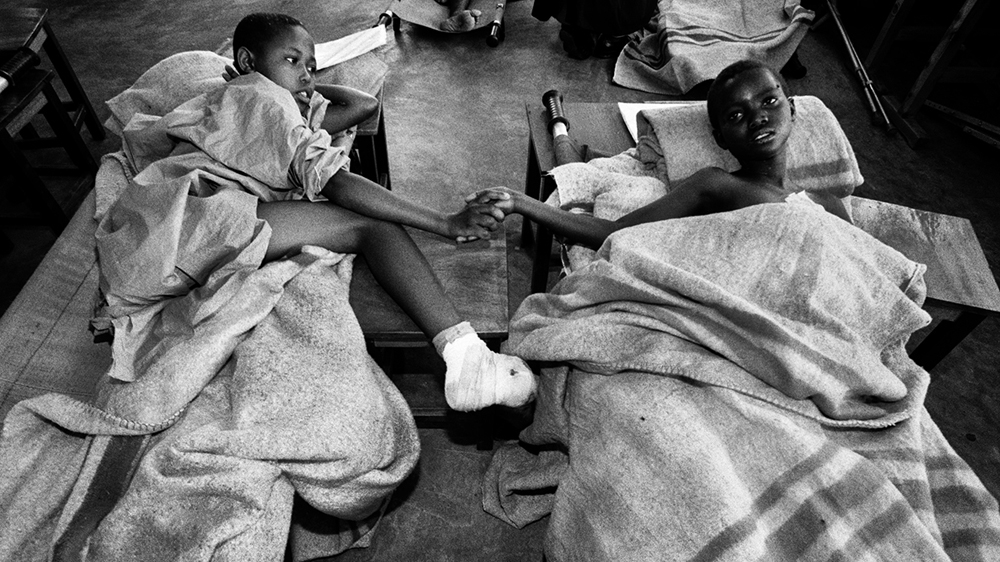 Two young boys who had limbs cut off with machetes comfort each other in a hospital in Kigali [Jack Picone/Al Jazeera]