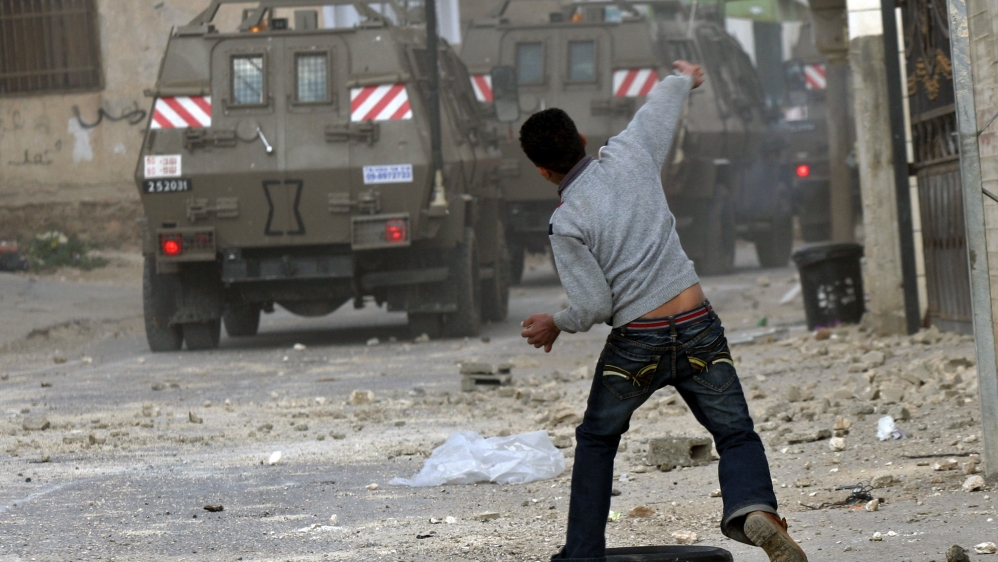 Palestinian youth throws stones at military