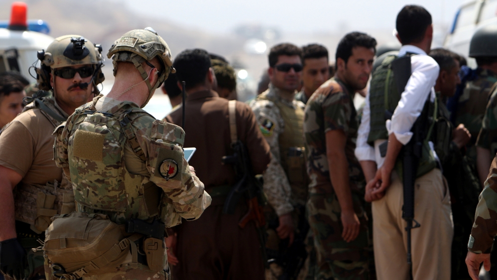 Soldiers from the U.S.-led coalition (L) are seen with Kurdish Peshmerga forces in a village east of Mosul