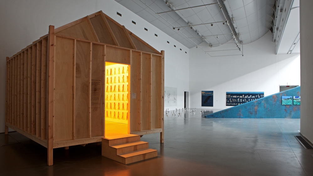 Sohee Cho's commissioned work 'Bongsunhwa Prayer 304', to the left, features photographs of the praying hands of people aged between two to 96. Yongju Kwon's 'Slanted', a free-standing wall to the right, resembles a rusted ferry [Gyeonggi MoMA]