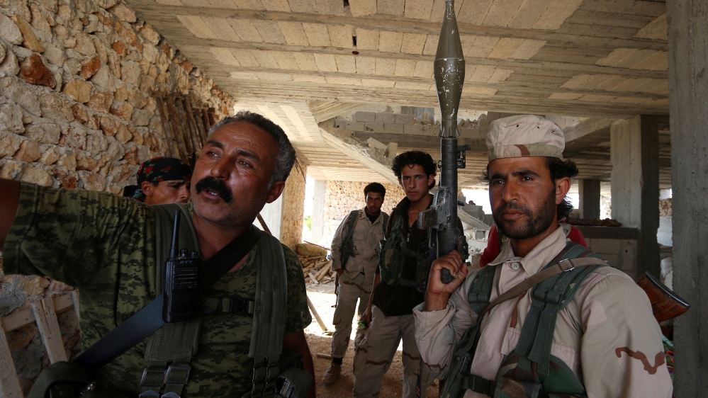 Fighters of the Syria Democratic Forces (SDF) stand inside a building near Manbij