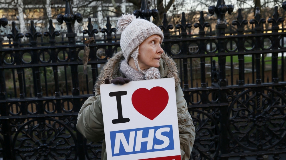 A woman holds a placard that reads ''I Love NHS'' during a strike outside St Thomas'' hospital in central London