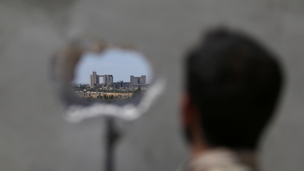 A Syria Democratic Forces fighter takes a position as he looks at Manbij''s mills where Islamic State militants are positioned, in Aleppo Governorate