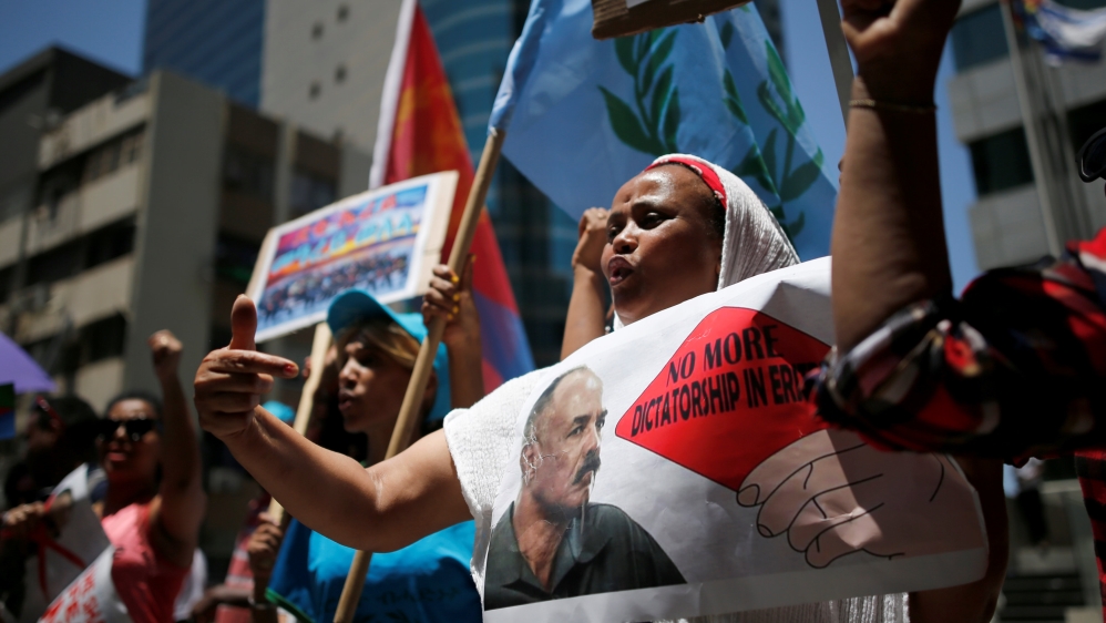 An Eritrean refugee holds a placard depicting Eritrea''s President Isaias Afwerki during a demonstration in support of a recent U.N. report that accused Eritrean leaders of committing c