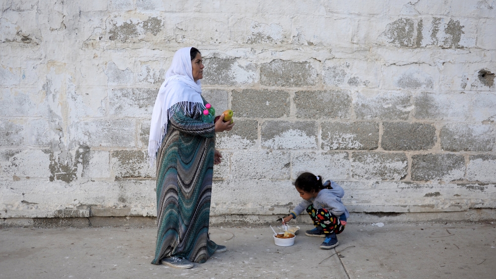 Refugees and migrants line up for food distribution at a temporary refugee camp on the Greek island of Leros