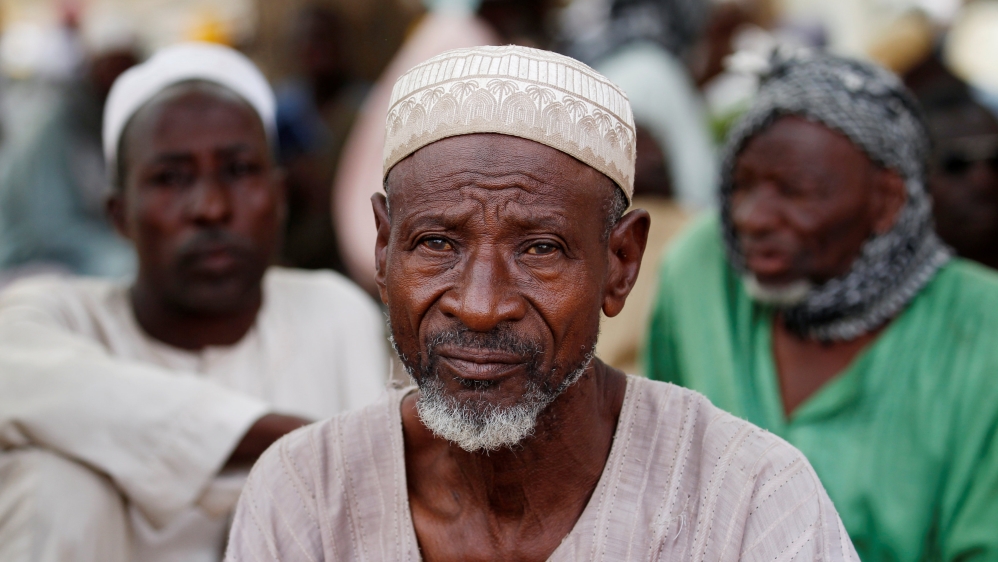 A Nigerian refugee, who fled from his village into Niger following Boko Haram attacks, looks on as he sits with his compatriots in the arena of traditional wrestling i