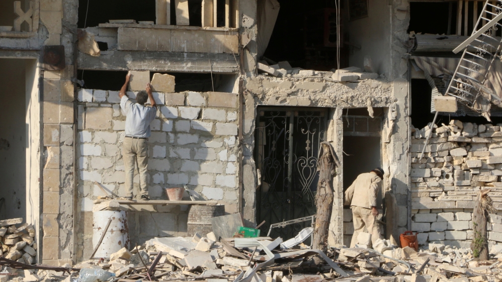 A man rebuilds a wall of a damaged building in the rebel held al-Katerji district in Aleppo