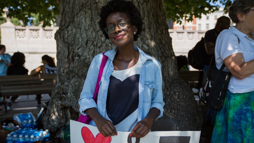 Barbara Okeny poses for a photograph as she waits for the Coalition's rally to begin   [Carolyn Bick/Al Jazeera]  