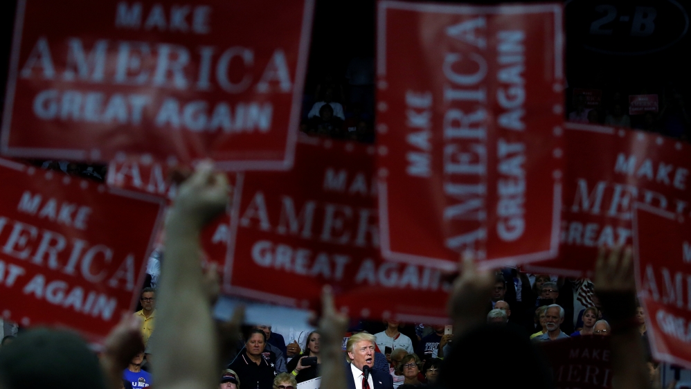 Republican presidential nominee Donald Trump is framed by "Make America Great Again" signs as he speaks onstage during a campaign rally in Akron