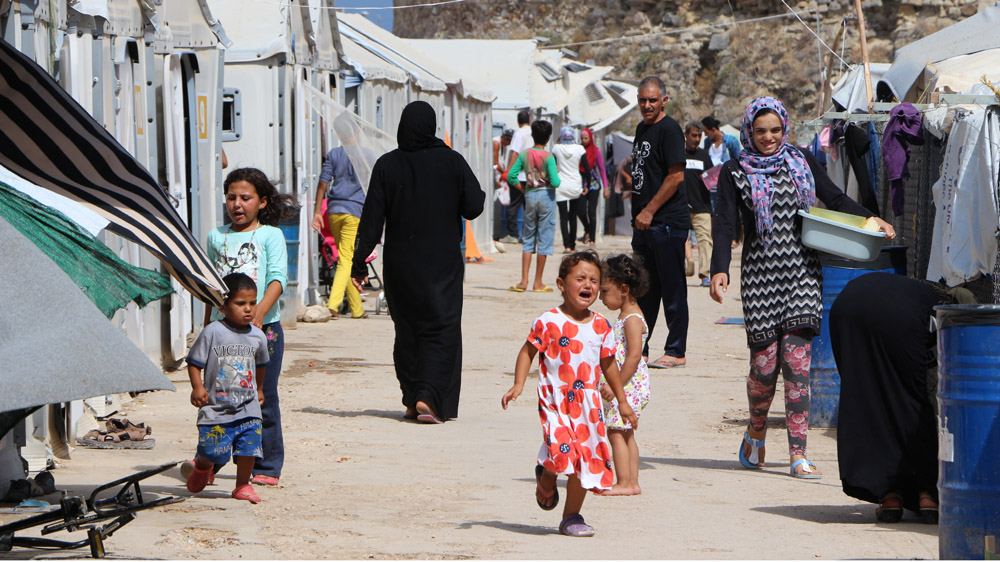  Refugees walk on the main street of the tent city at Souda, outside the Venetian fortress, in Chios town   [John Psaropoulos/Al Jazeera]
