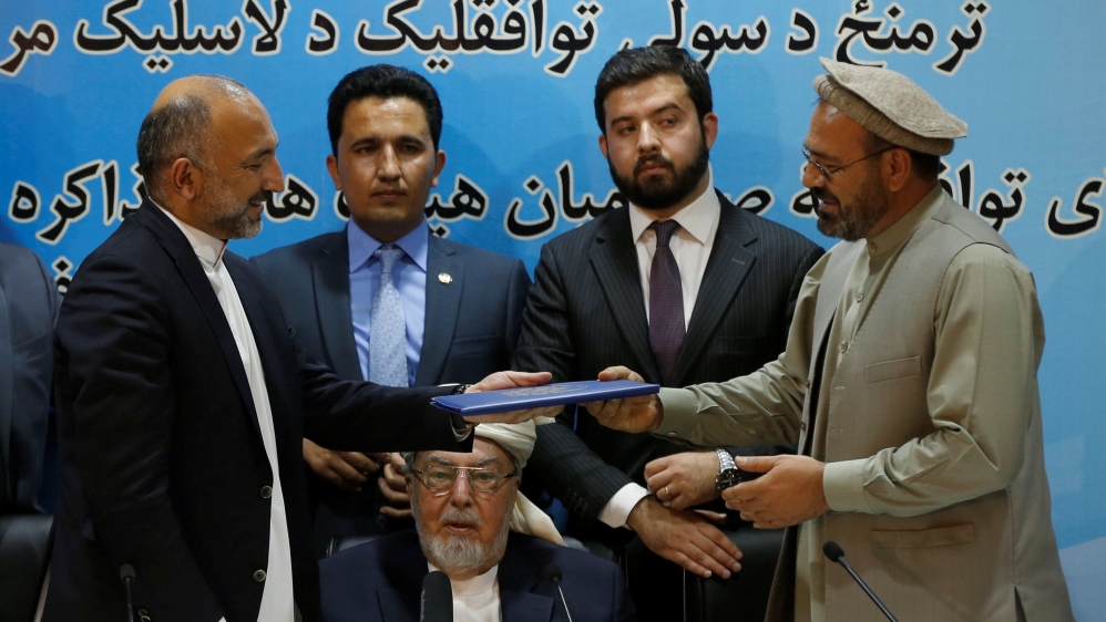 Karim and Atmar hold a document after signing a peace deal in Kabul
