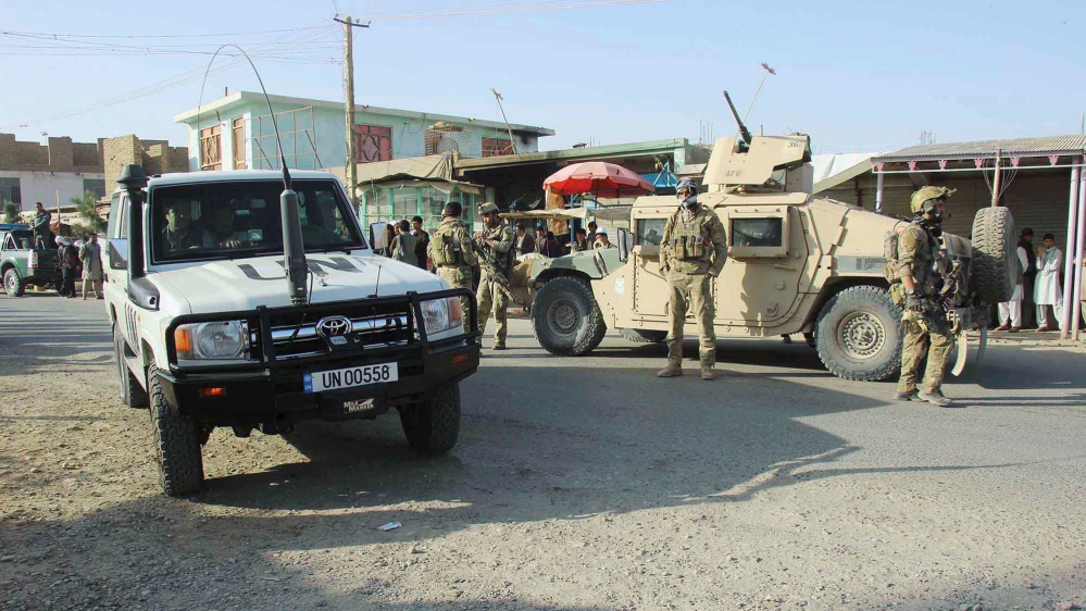 Afghan security forces keep watch in front of their armoured vehicle in Kunduz city