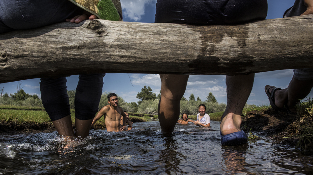 A herding family plays in a stream in Ikh Tamir. Participating in a PUG has let herders reap greater financial returns through collective negotiations to get higher prices [Taylor Weidman/Al Jazeera