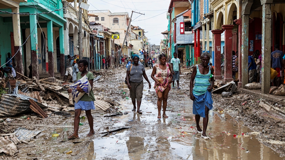 People walk along a street in downtown as clean up from Hurricane Matthew continues in Jeremie