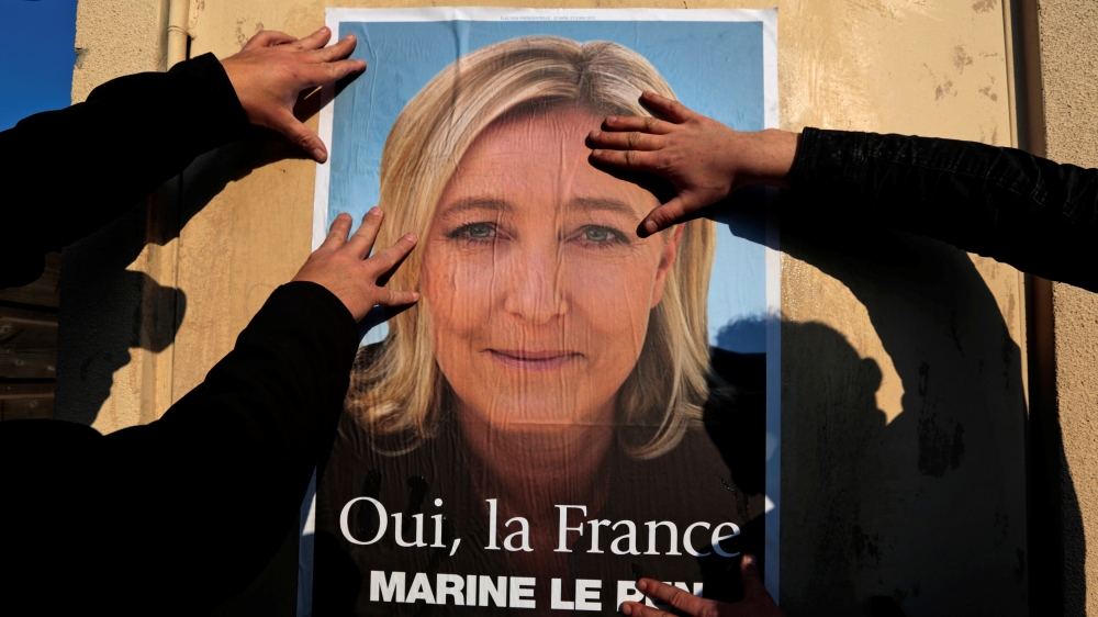 Supporters paste a poster of Marine Le Pen, France''s National Front leader, on a wall before a political rally for local elections in Frejus