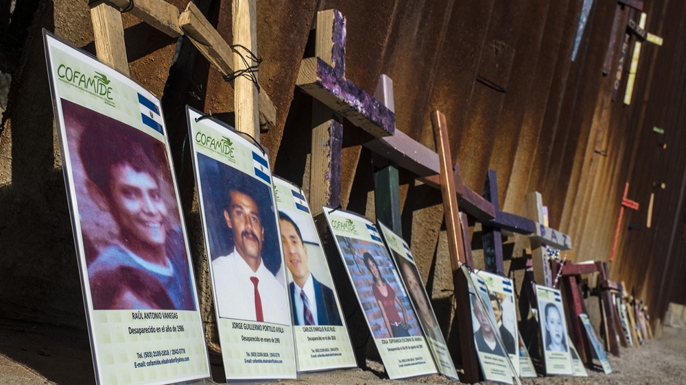 Mothers from the caravan put the images of disappeared migrants against the separation wall in Nogales Mexico. The militarisation of the border, forces migrants to walk much further into the desert, in order to avoid immigration officials, and risk their lives trying to cross irregularly into the US [Encarni Pindado/Al Jazeera]