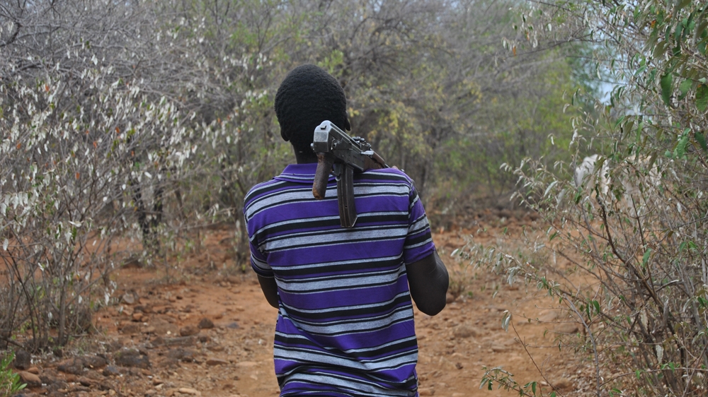 A herder from Sinoni village heads towards grazing fields by a river which divides his Tugen and the Pokot tribes [Anthony Langat/Al Jazeera]