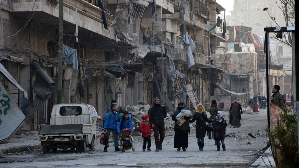 People, who evacuated the eastern districts of Aleppo, carry their belongings as they arrive in a government held area of Aleppo