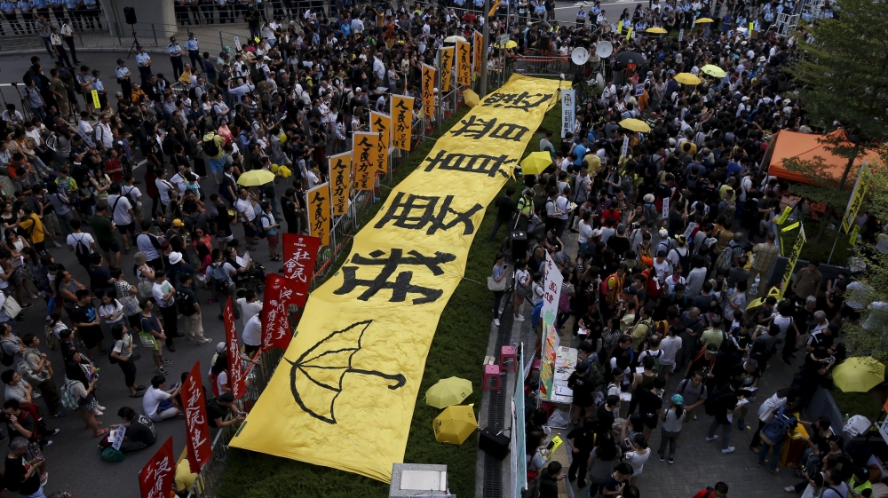 Pro-democracy protesters gather next to a banner which reads 'I need real universal suffrage', outside government headquarters in Hong Kong, China, in 2015 [Bobby Yip/Reuters] 