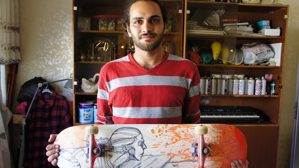Attar stands with a skateboard that he customised and designed at his home in east Amman [Zab Mustefa/Al Jazeera]