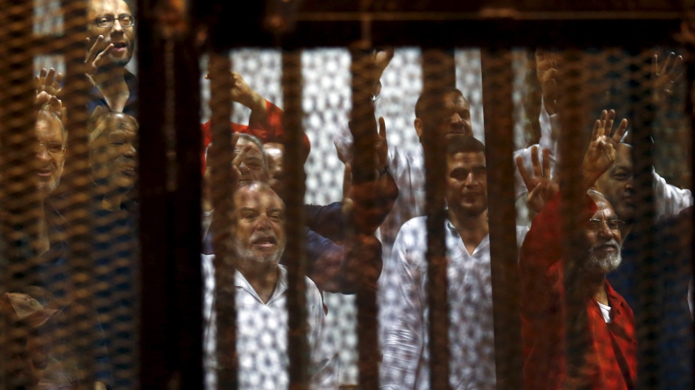 Muslim Brotherhood members wave with the Rabaa sign, symbolizing support for the Muslim Brotherhood, with other brotherhood members at a court in the outskirts of Cairo, Egypt