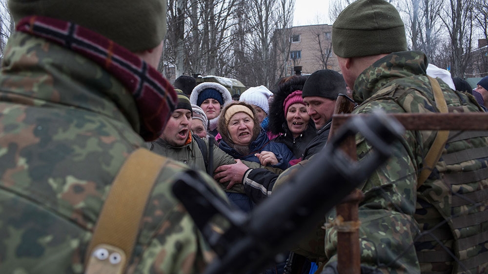 People from Avdiivka seeking humanitarian aid fight for a place at the front of the line while Ukrainian soldiers work to control the crowds [John Wendle/Al Jazeera]