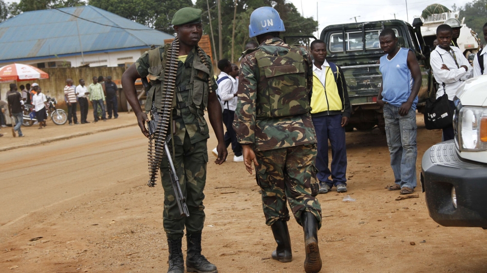 A peacekeeper serving in the MONUSCO and a Congolese soldier stand guard as residents gather following recent demonstrations in Beni in North Kivu province