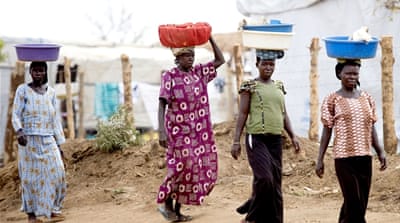 Women in the Bidibidi settlement carry food after an aid distribution [Yilmaz Polat/Al Jazeera]