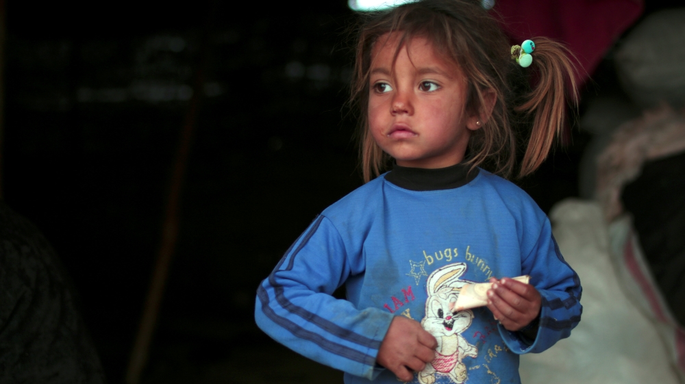 An internally displaced Syrian woman rests near cushions in Manbij city