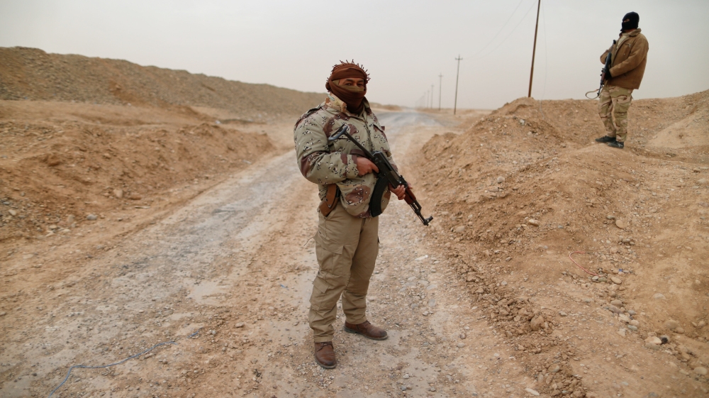 Members of tribal fighters carry weapons during clashes with Islamic State militants at the south of Mosul