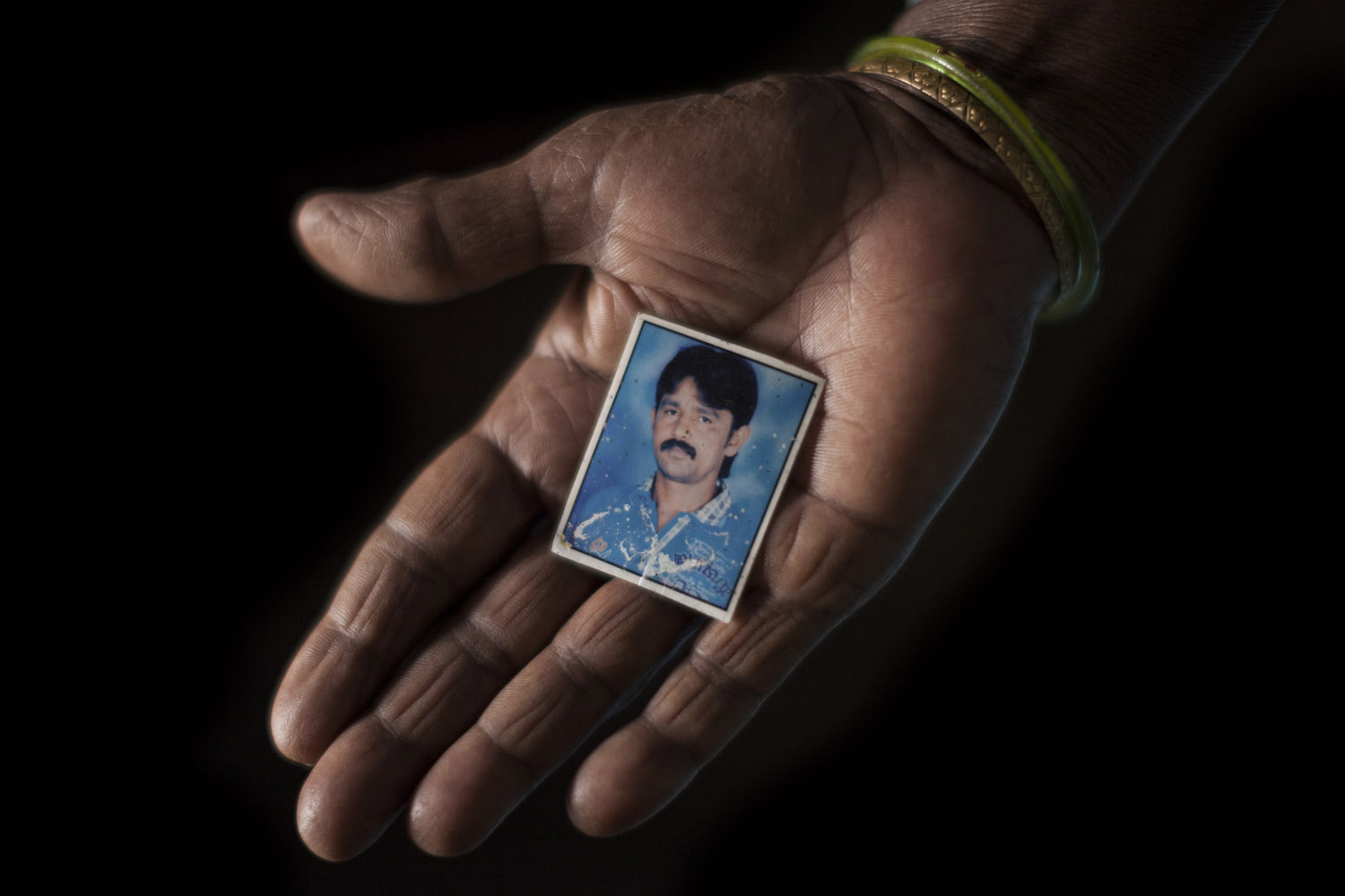 Savithriamma holds a photograph of her son Shivanna [Janos Chiala/Al Jazeera]