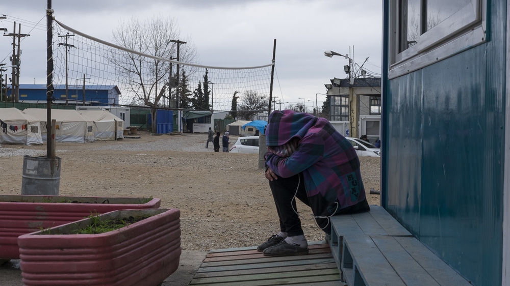 A young Afghan girl listens to music on her mobile phone to pass the time at a camp in Oinofyta, a small town on the outskirts of Athens [Fahrinisa Oswald/Al Jazeera] 