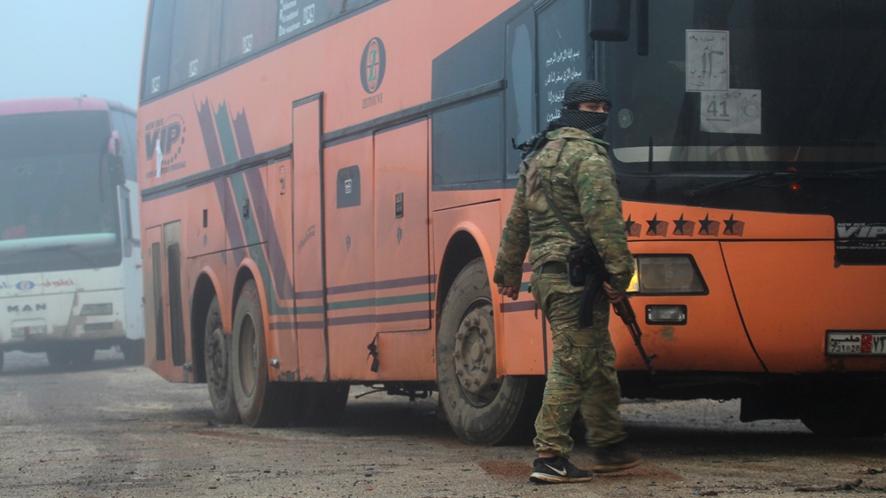 A rebel fighter stands near buses carrying people evacuated from the two villages of Kefraya and al-Foua