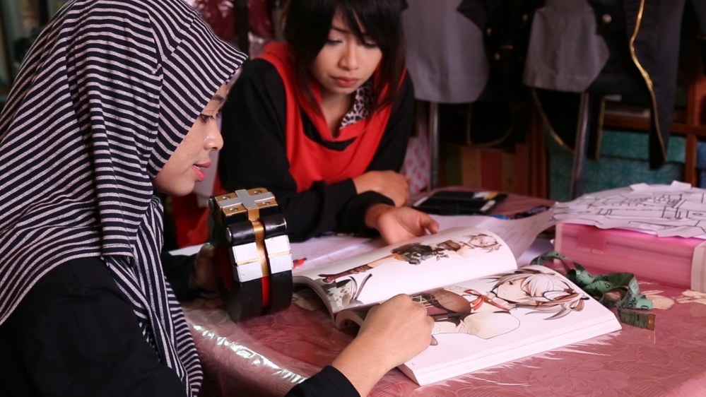 Hafizah Rashid and her sisters plan their costumes. [Preeti Jha/Al Jazeera]