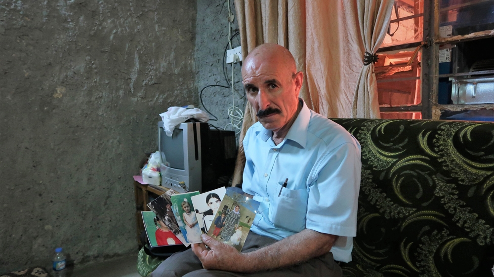 Showing pictures of his abducted children and wife, Haji says: 'I lost everything when ISIL attacked us' [Brenda Stoter/Al Jazeera]