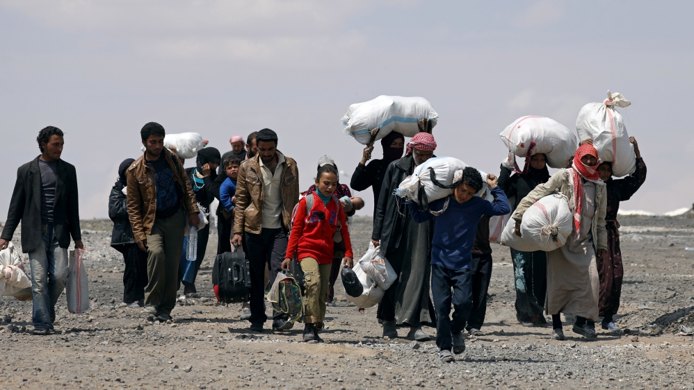 Internally displaced people who fled Raqqa city carry their belongings as they leave a camp in Ain Issa