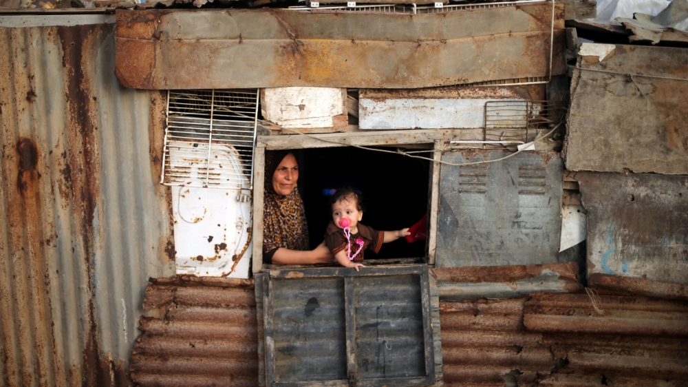 A Palestinian woman and her child look out of the window of their shelter in Deir al-Balah refugee camp in the central Gaza Strip, July 29, 2016 [Reuters]