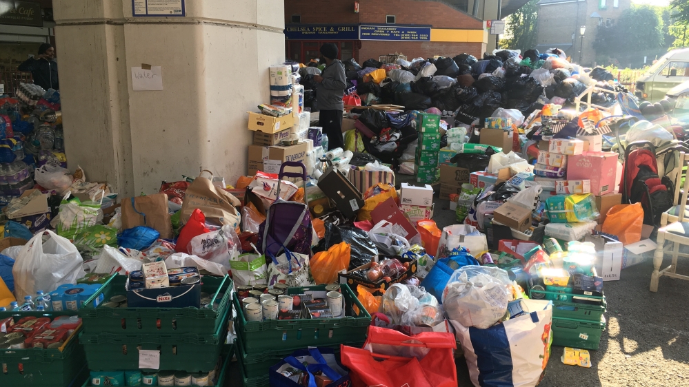 Food, drink and other supplies are stored beneath a flyover near the burned building in west London [Reuters]