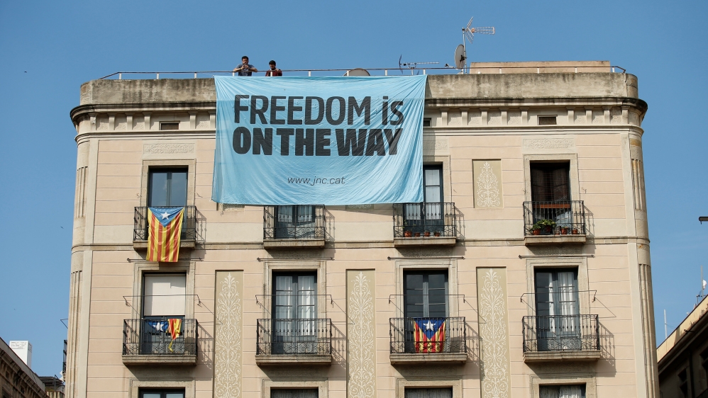 Catalonia independence supporters unfurl a banner on a building next to the Palau de la Generalitat, the regional government headquarters, in Barcelona
