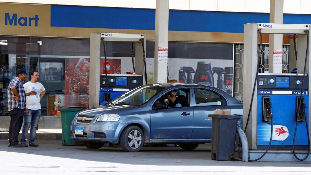 Vehicles are seen being filled up with fuel by employees at a Mobil petrol station in Cairo