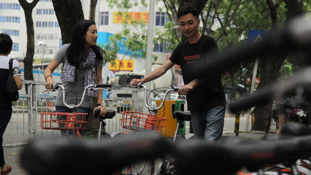 Stephanie Wong takes one of Shenzhen's dockless city cycles for a test ride [Al Jazeera]