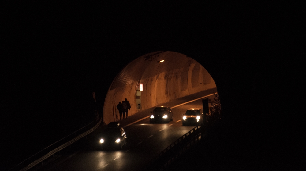Three Sudanese men walk the motorway to France, on the other side of the tunnel [Maurizio Martorana/Al Jazeera]