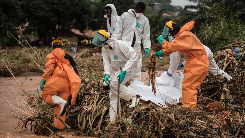 Body collectors pull a mangled foot from the rubble six days after the mudslide [Olivia Acland/Al Jazeera]