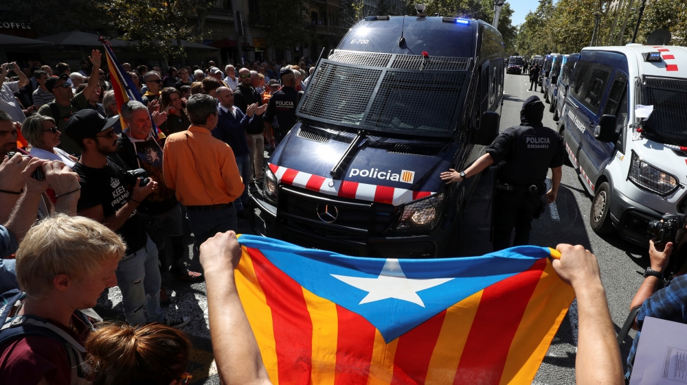 A protestor holds up an Estelada (Catalan separatist flag) in front of a Catalan police van outside the Catalan region''s economy ministry building during a raid by Spanish police on several government