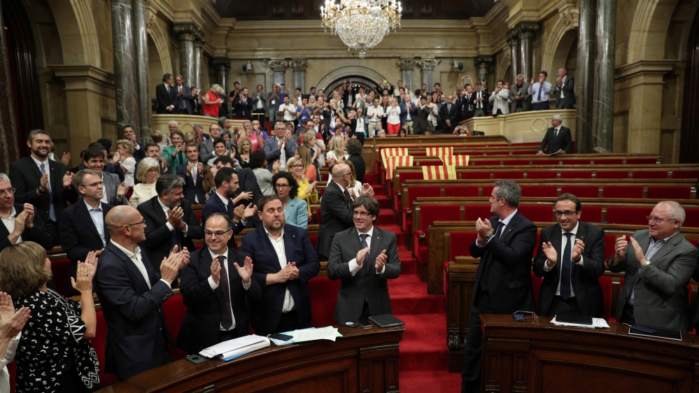 Catalan regional President Carles Puigdemont stands with deputies after voting to hold a referendum in the Catalonian regional Parliament in Barcelona