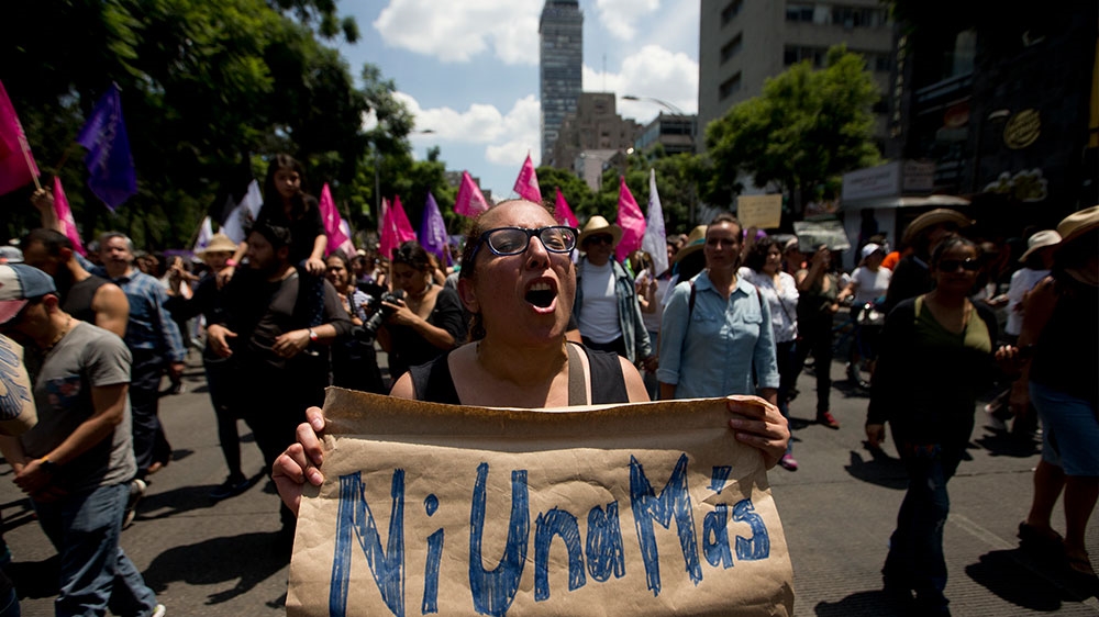 A woman marches holding a sign that reads in Spanish 