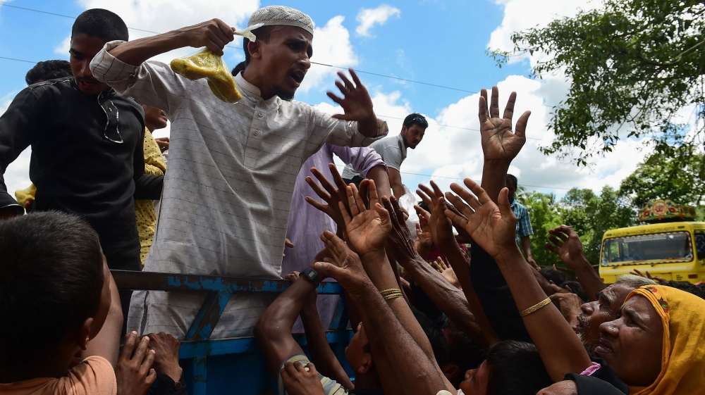Rohingya refugees from Myanmar gesture towards a man on a truck delivering food aid in Ukhia, Bangladesh [Munir Uz Zaman/AFP]