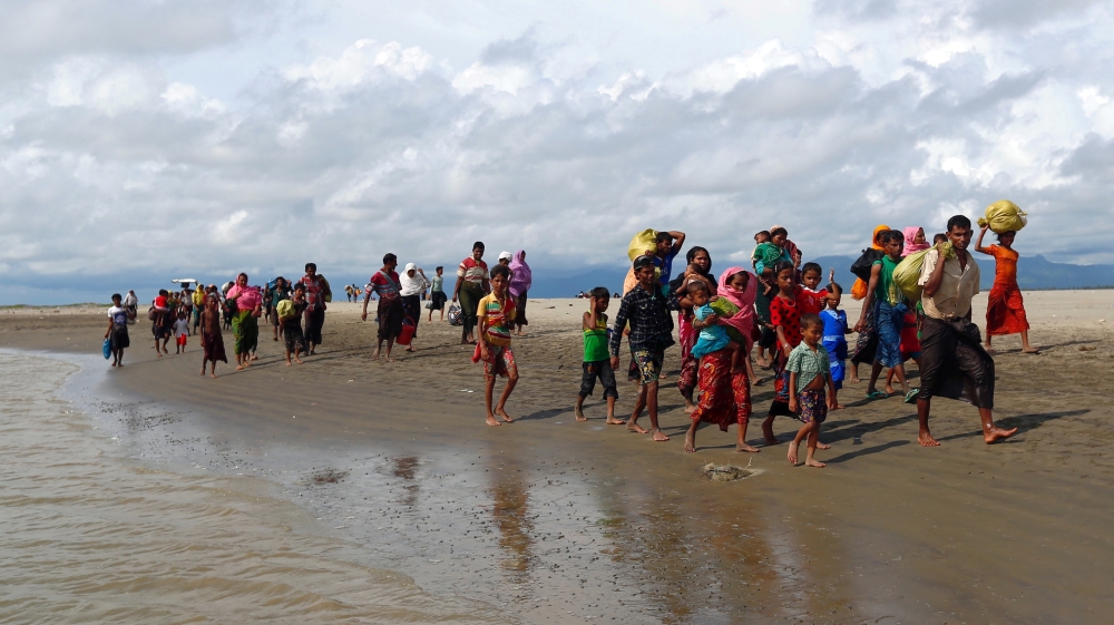 Rohingya refugees walk on the shore after crossing the Bangladesh-Myanmar border by boat through the Bay of Bengal in Shah Porir Dwip